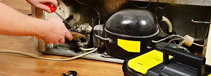Refrigerator repair technician fixing the compressor and wiring in Star, ID