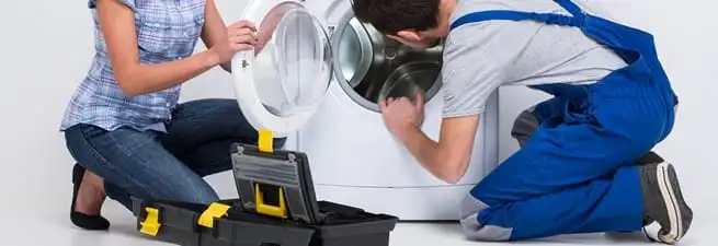 Washer repair technician inspecting a front-load washing machine with tools in Boise, ID