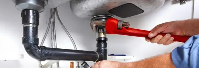 Garbage disposal repair technician tightening the sink drain and disposal connection in Boise, ID