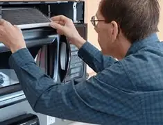 Appliance repair technician replacing a microwave vent filter in Boise, ID