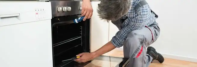 Oven repair technician inspecting and servicing an electric oven in Boise, ID