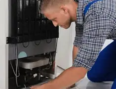 Refrigerator repair technician servicing the compressor and condenser area in Boise, ID