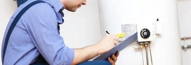Water heater repair technician inspecting the unit and recording service notes in Boise, ID